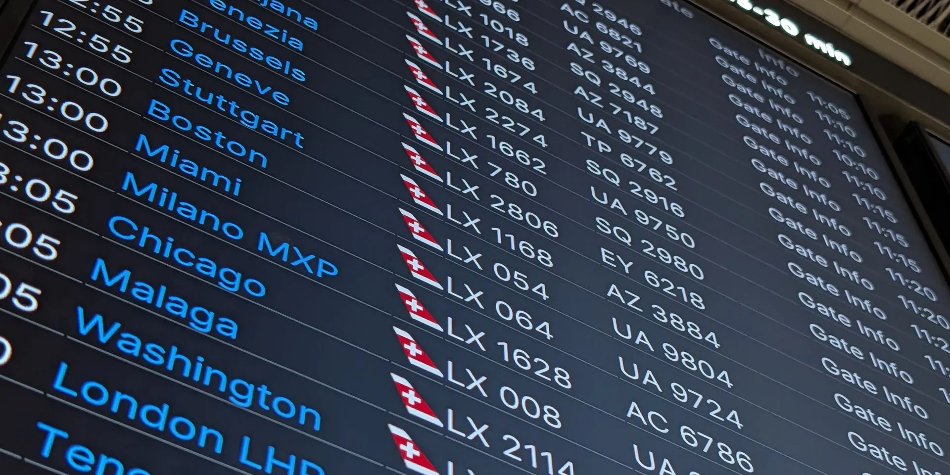 A departures board at Zurich Airport listing flights to Malaga, Washington, London and Tokyo with their departure times and flight numbers