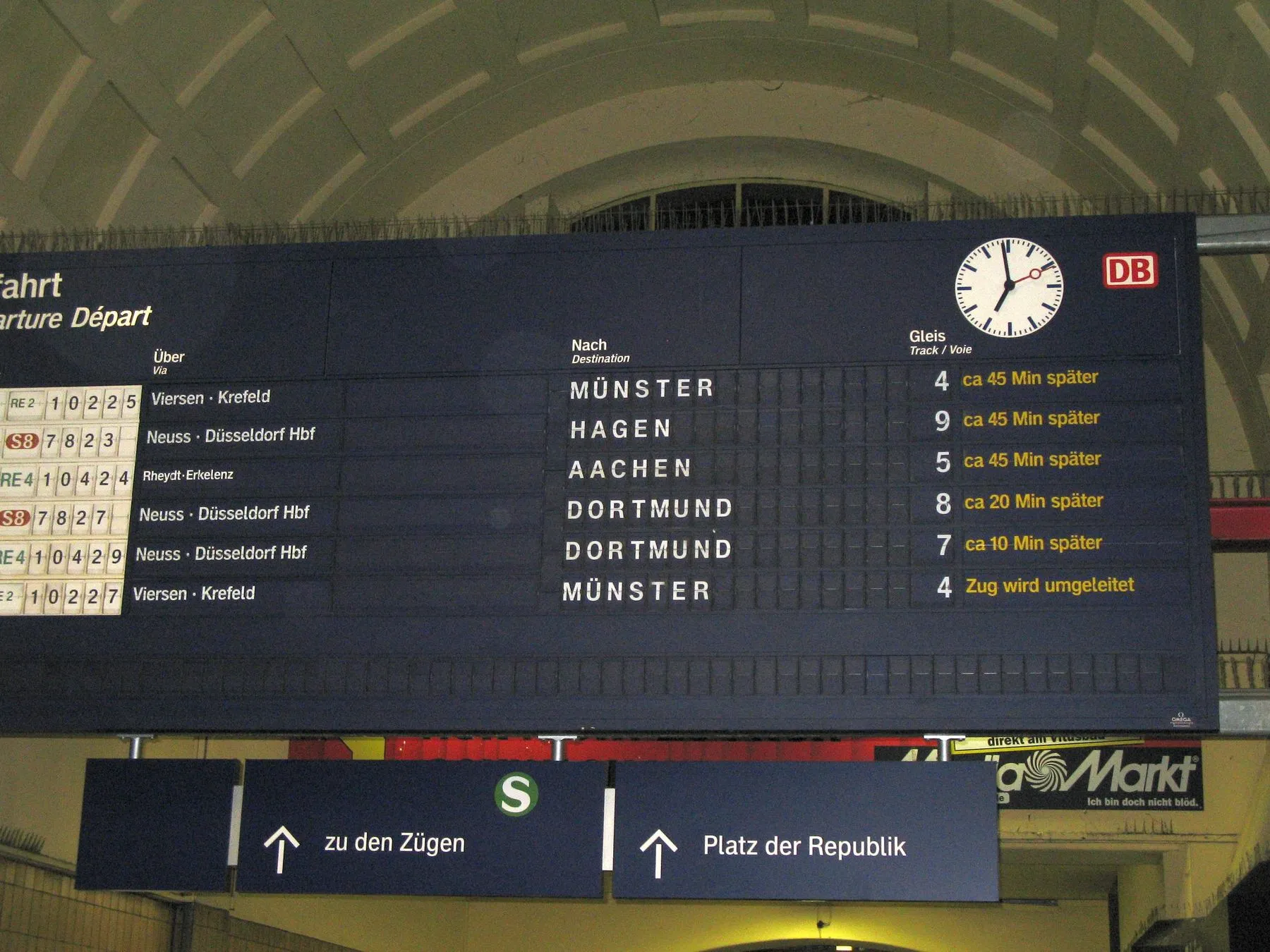 Panel de salidas de la estación central de Mönchengladbach con trenes que salen entre 10 y 45 minutos tarde y un tren desviado