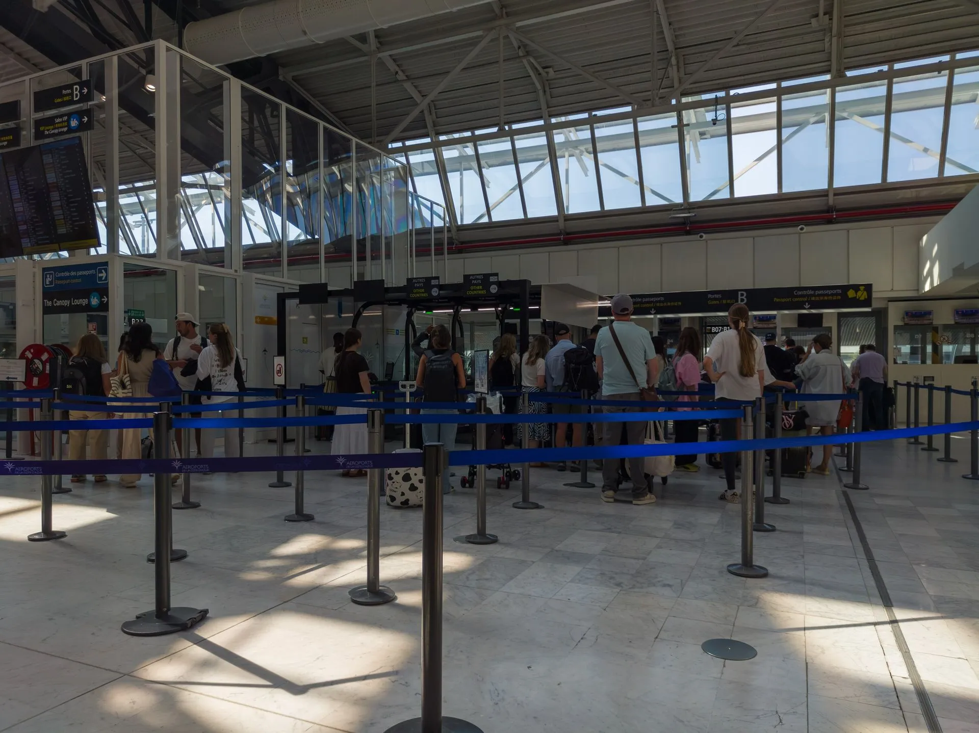 Travelers queue between blue barrier tapes for passport control at Nice Côte d’Azur Airport