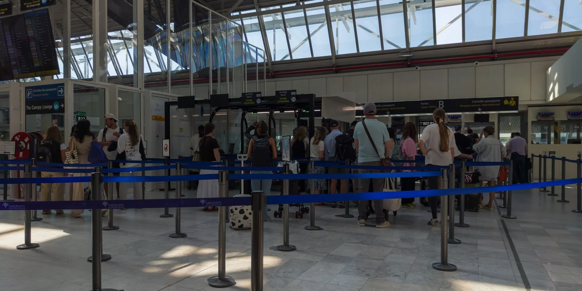 Travelers queue between blue barrier tapes for passport control at Nice Côte d’Azur Airport