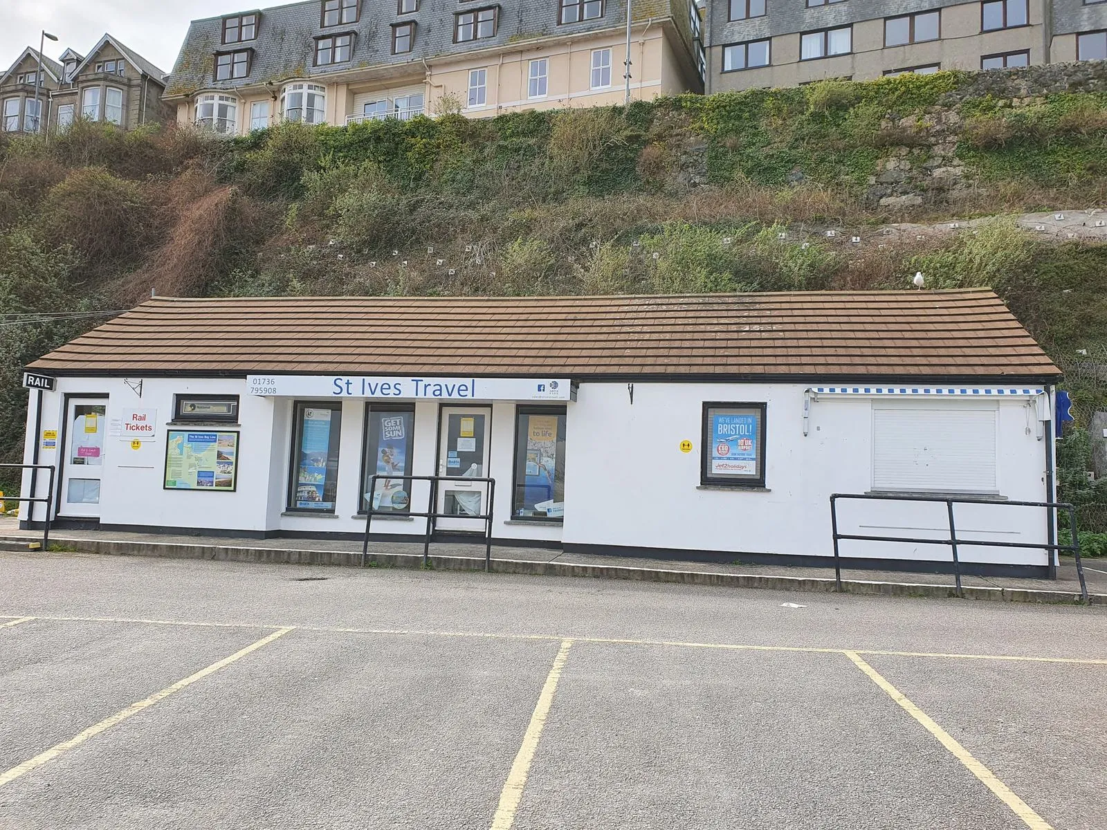 St Ives Travel, una pequeña agencia de viajes en un edificio de una sola planta en St Ives (Cornualles), con carteles y ofertas en los escaparates