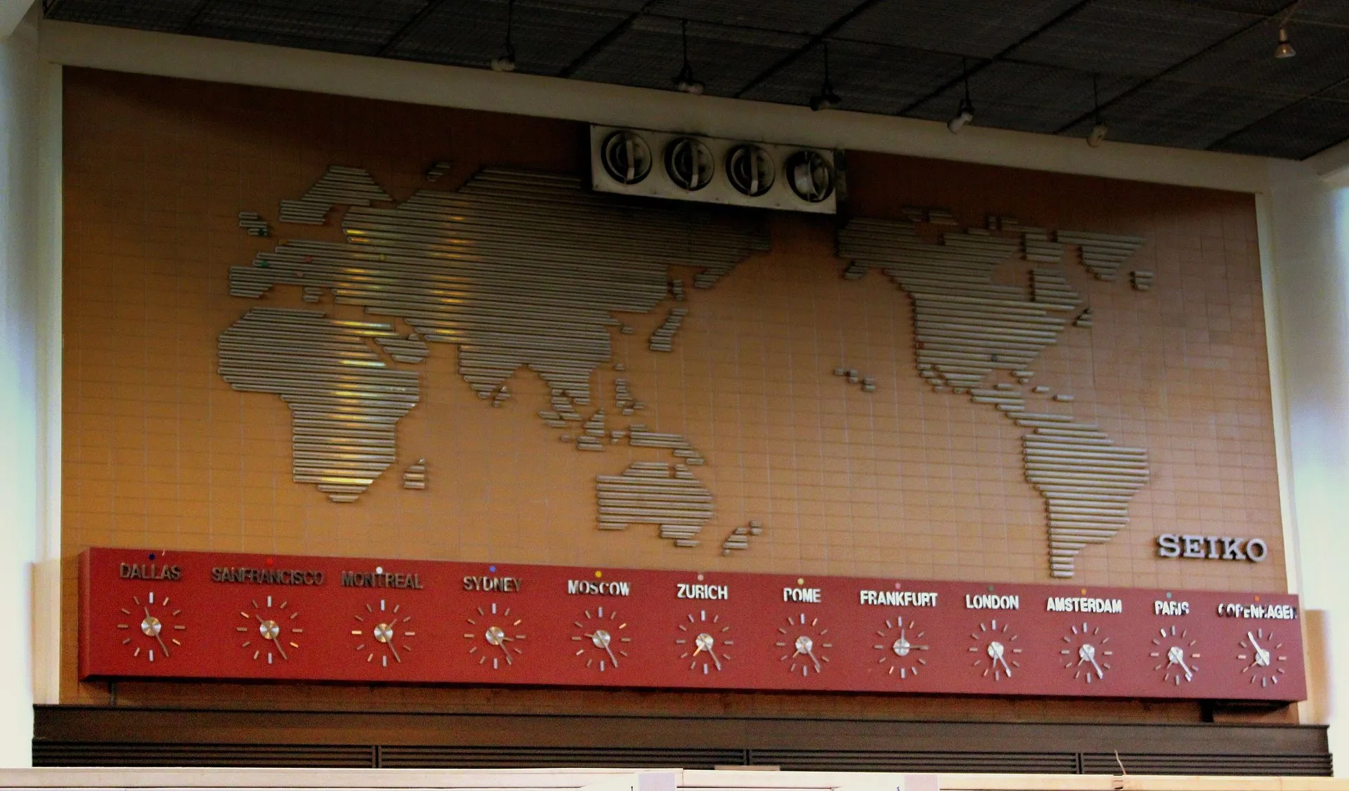 Una pared de relojes en el aeropuerto Don Mueang de Bangkok con la hora de ciudades como Dallas, Sídney, Moscú, Londres y París bajo un mapamundi
